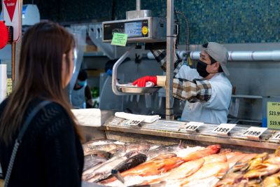 Person weighing fish for a customer at a seafood market.