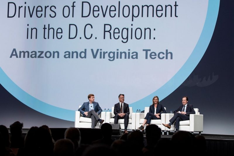 Four people on a stage at a conference for urban development