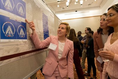 Katie Gottleib (at left) presenting her research poster while participants ask questions.