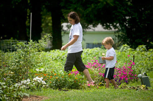 Gardens Growing Families participants Laurel Cosby and son Ivan water their garden plot.