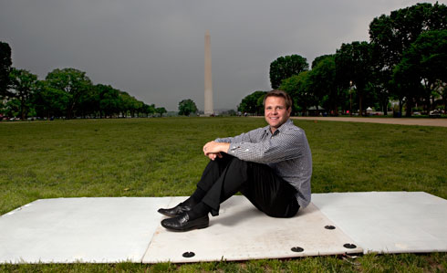 John Royse sits in front of the National Mall and Memorial Parks in Washington, D.C., on one of the lighted grass panels he researched at Virginia Tech.