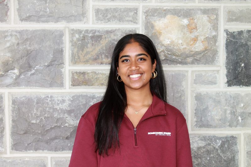 student standing and smiling in front of a Hokie Stone background