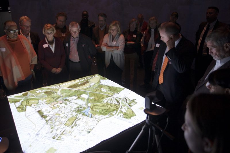 Members of the Virginia Tech Board of Visitors look at a table containing a map of campus